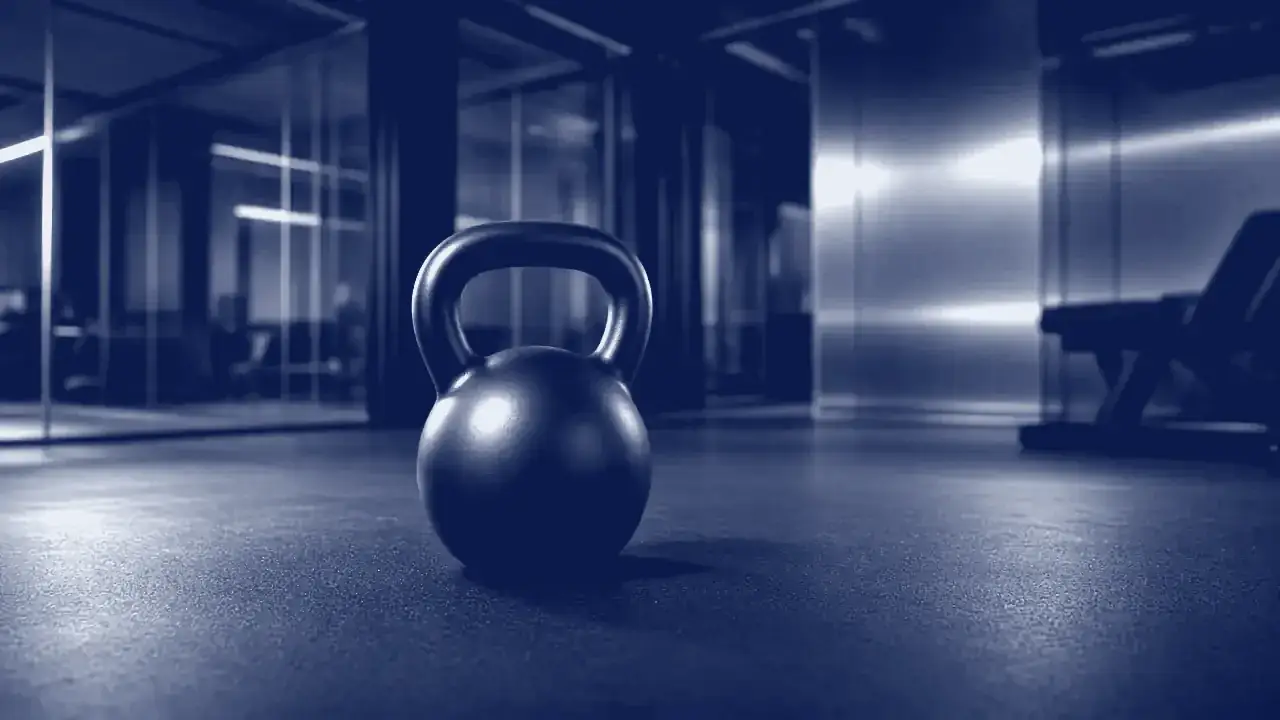 A kettlebell on a dark gym floor in cool blue light